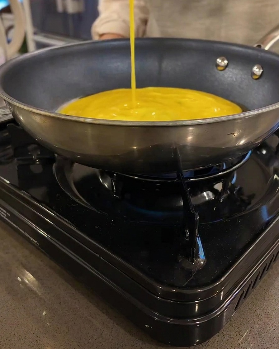 Cienki żółty omlet smażący się na płaskiej patelni.