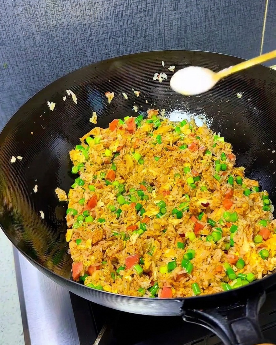 Zbliżenie na sól i bulion w proszku posypywane na kolorowy ryż smażony z kimchi w woku.