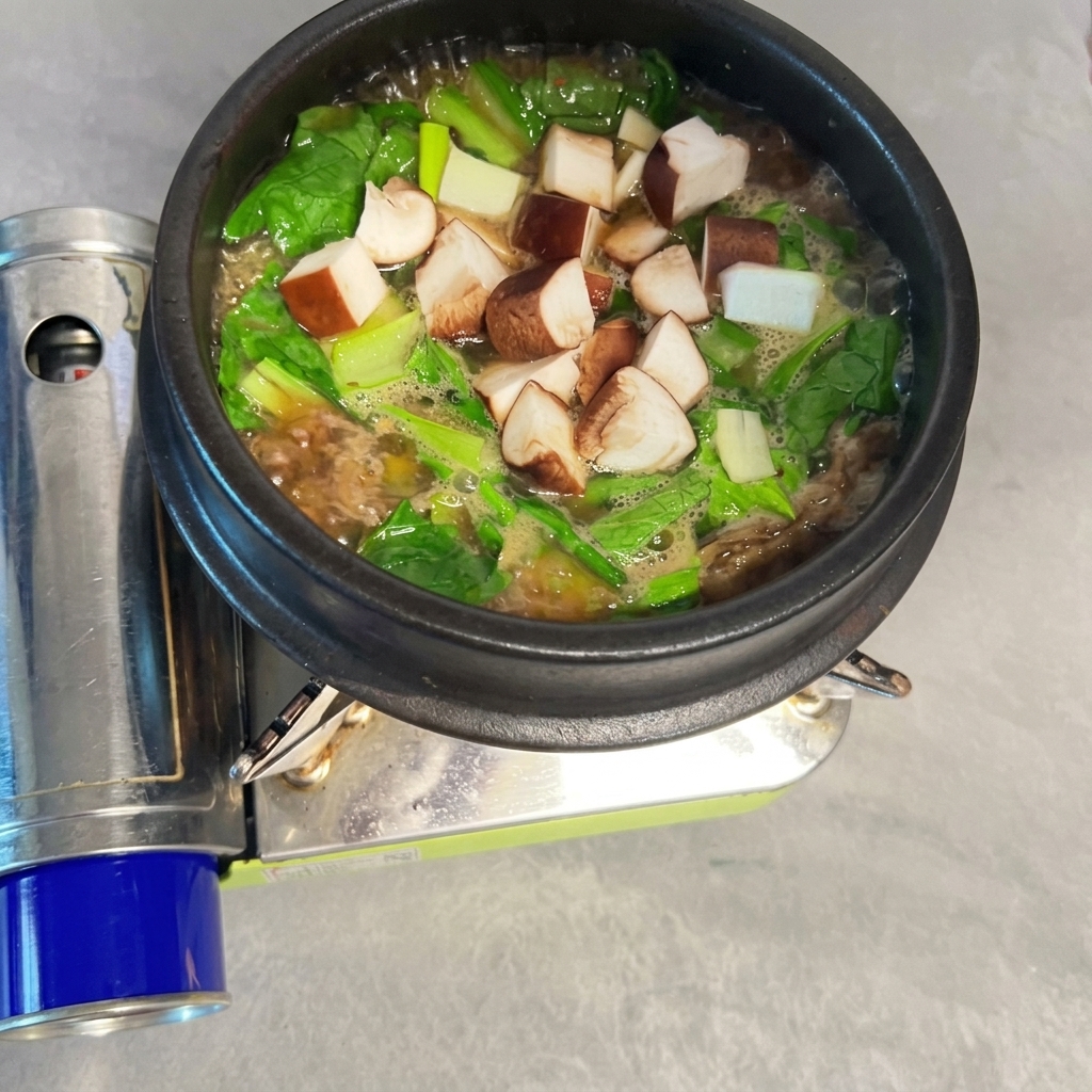 Pokrojone grzyby shiitake rozsypane w bulgoczącym Doenjang-jjigae.