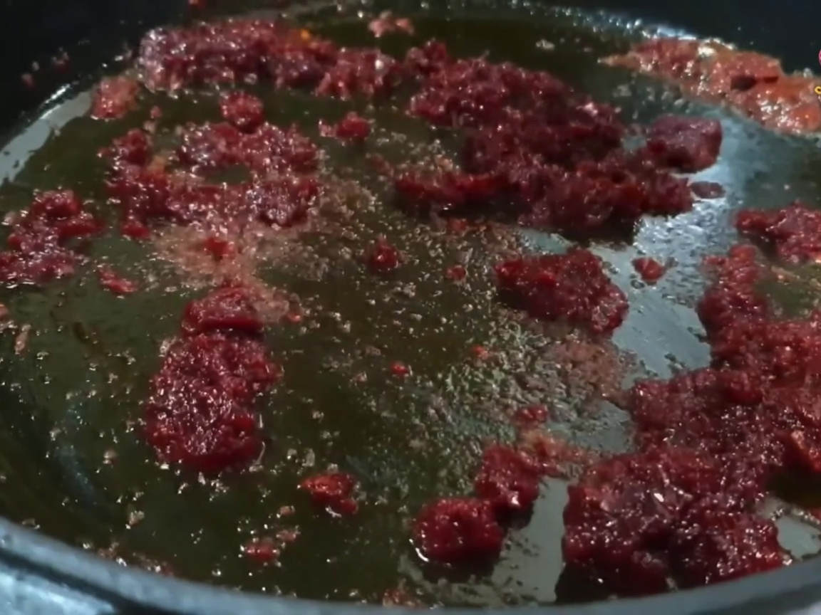 Małe kawałki wieprzowiny mieszane i podsmażane na patelni z jaskrawoczerwoną mieszanką oleju chili.