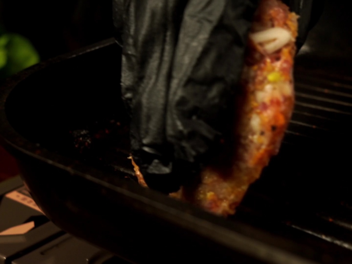 Surowy kotlet wołowy kładziony na rozgrzaną patelnię grillową.