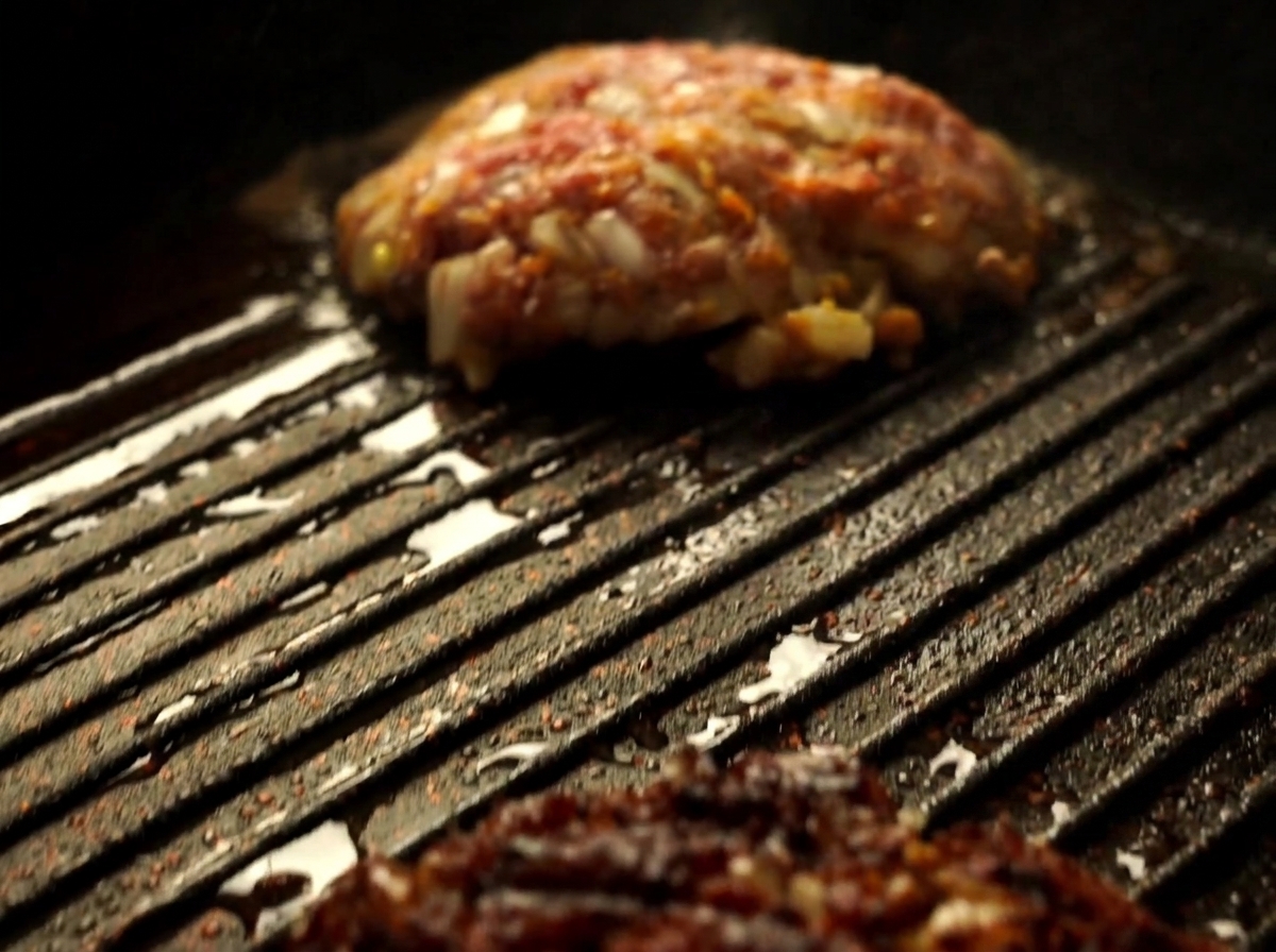 Zbliżenie na kotlet z wołowiny Wagyu odwracany szpatułką na gorącej patelni grillowej.
