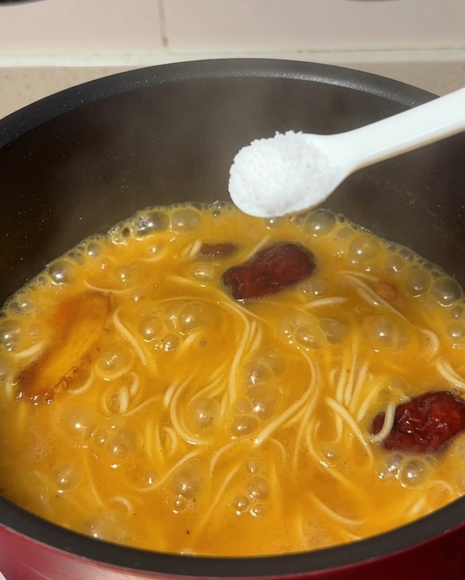 Łyżka soli dodawana do garnka z gotującym się makaronem i rosołem.