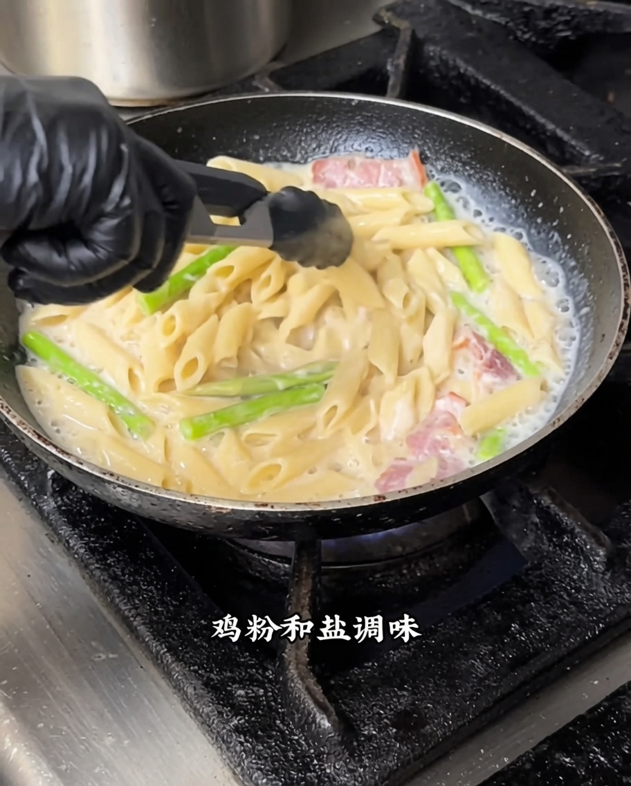 Makaron penne mieszany z białym sosem i czarną truflą na patelni na średnim ogniu.