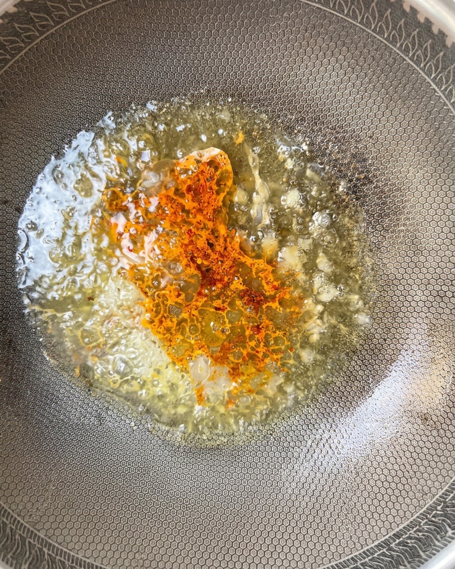 Chili w proszku posypywane do bulgoczącego sosu w woku.