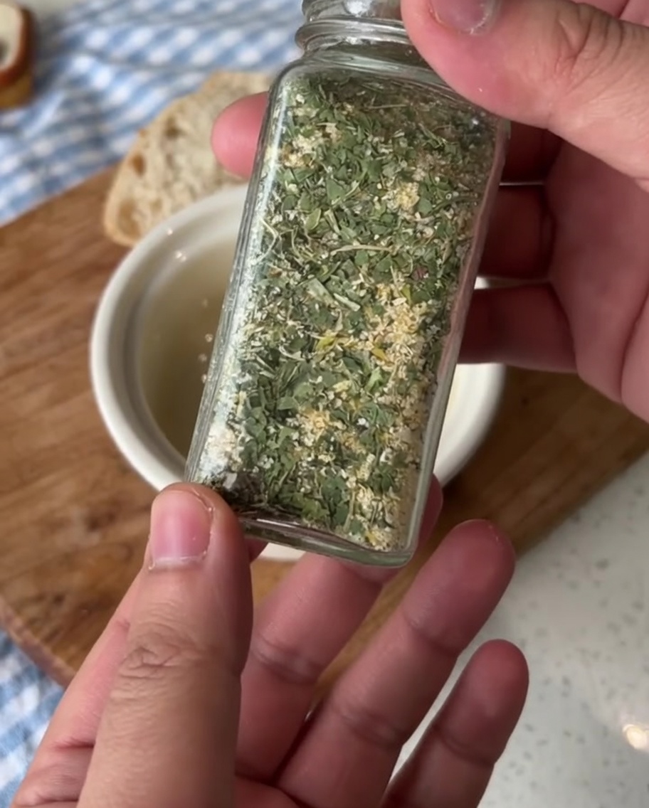 Mała ceramiczna miseczka z miękkim masłem, przyprawianym zieloną pietruszkową solą czosnkową.
