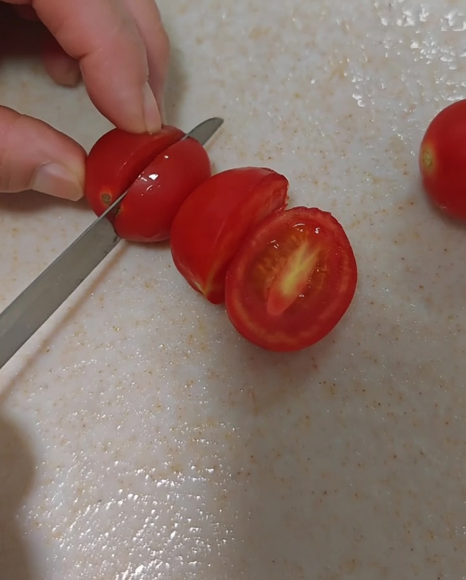 Świeże pomidorki koktajlowe ostrożnie krojone na pół.