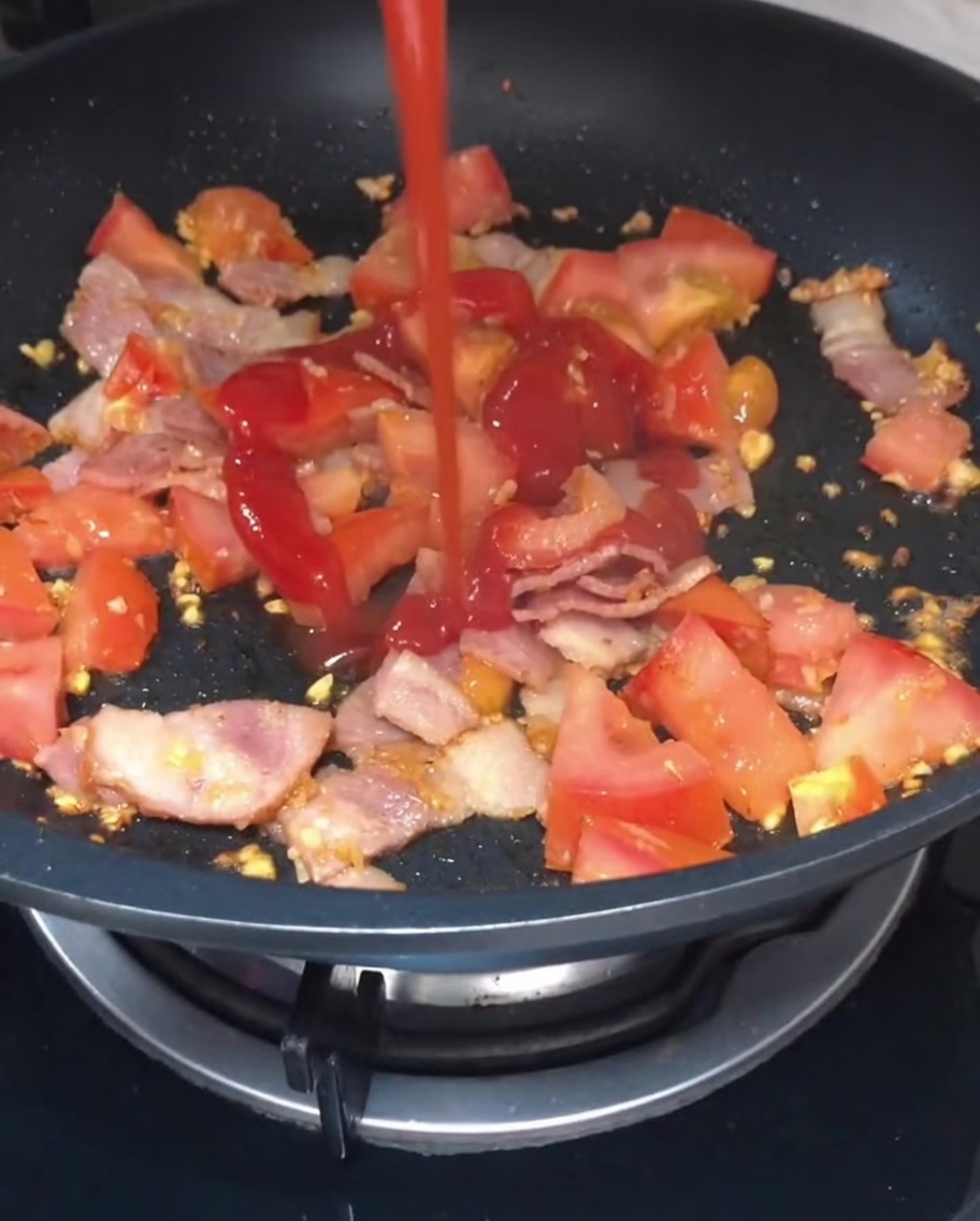 Ketchup i jasny sos sojowy polewane na podsmażoną mieszankę pomidorów i bekonu.