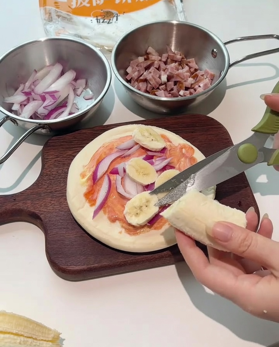 Nożyczki kuchenne krojące świeżego banana bezpośrednio na pizzę.