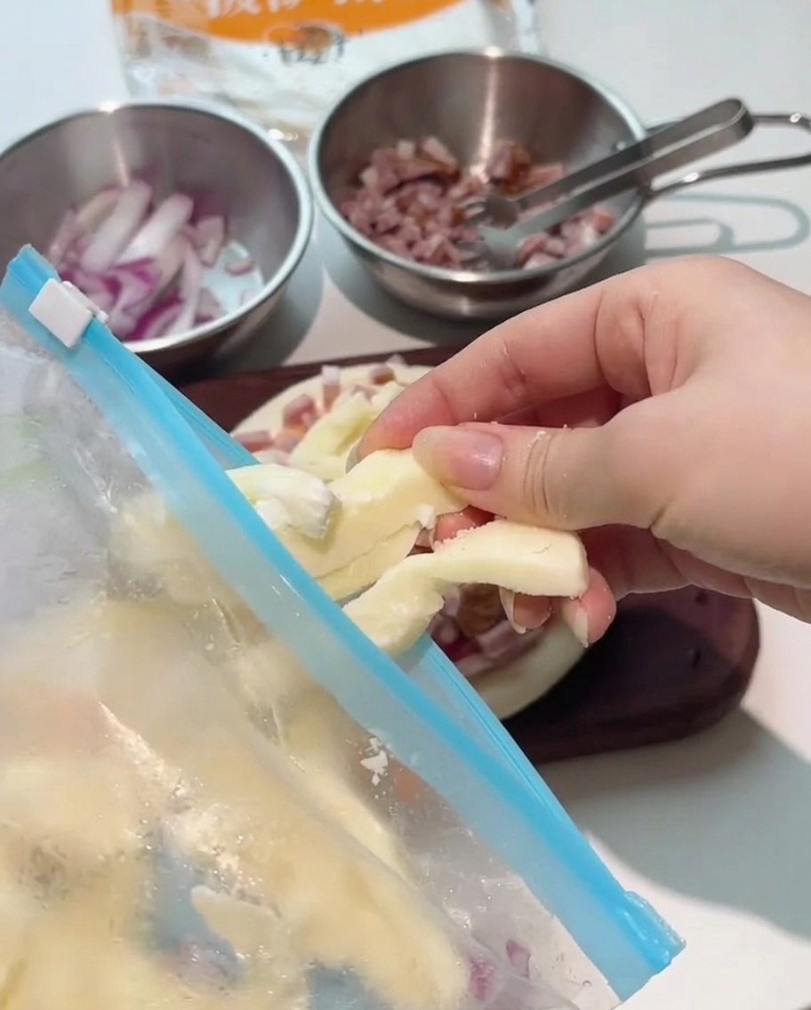 Grube paski sera mozzarella układane na dodatkach na pizzy.