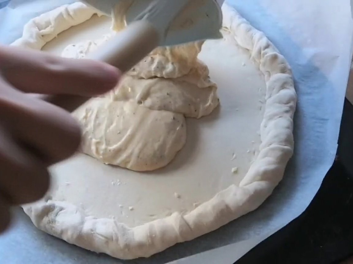 Plasterki pepperoni i salami ułożone na pizzy z sosem.