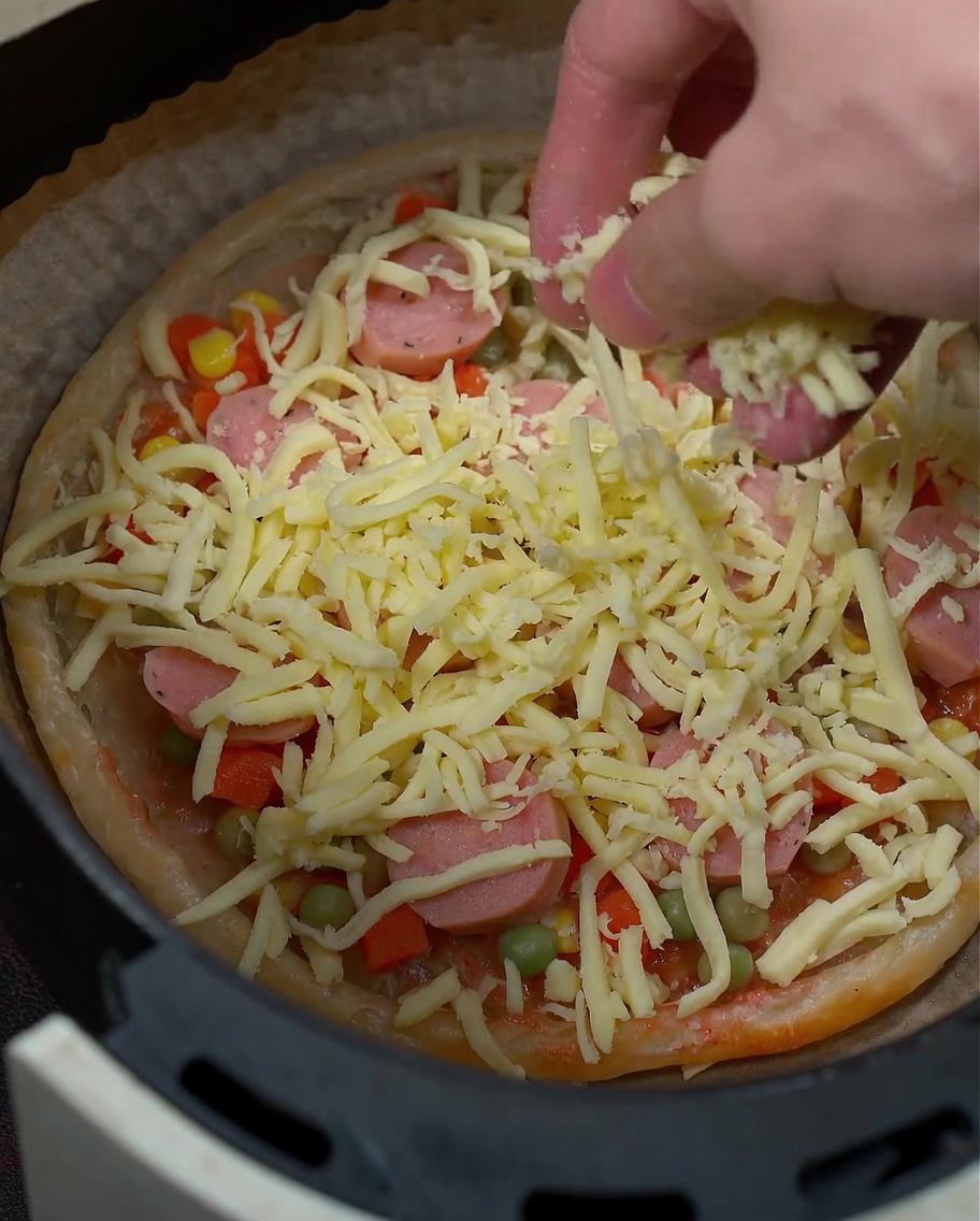 Zbliżenie na ser mozzarella posypywany na składniki pizzy.