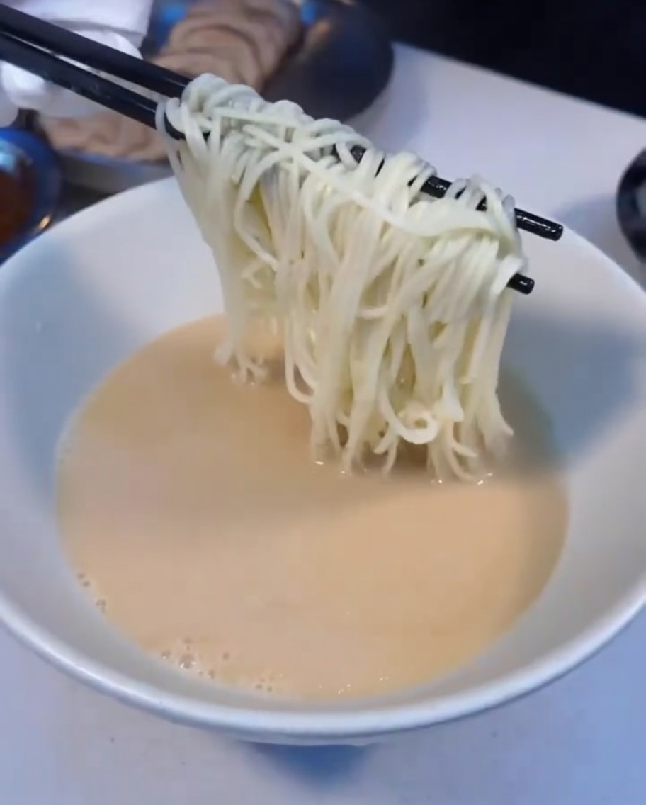 Gorący makaron ramen przekładany do miski z zupą.