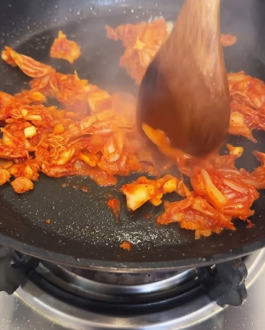 Woda wlewana na patelnię z podsmażonym kimchi i czosnkiem.