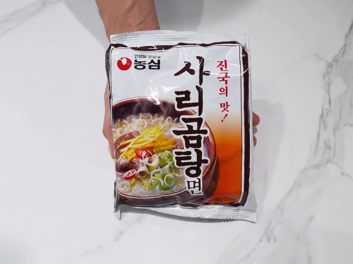 Blok makaronu ramen dodany do gotującego się bulionu z wieprzowiną i kimchi.