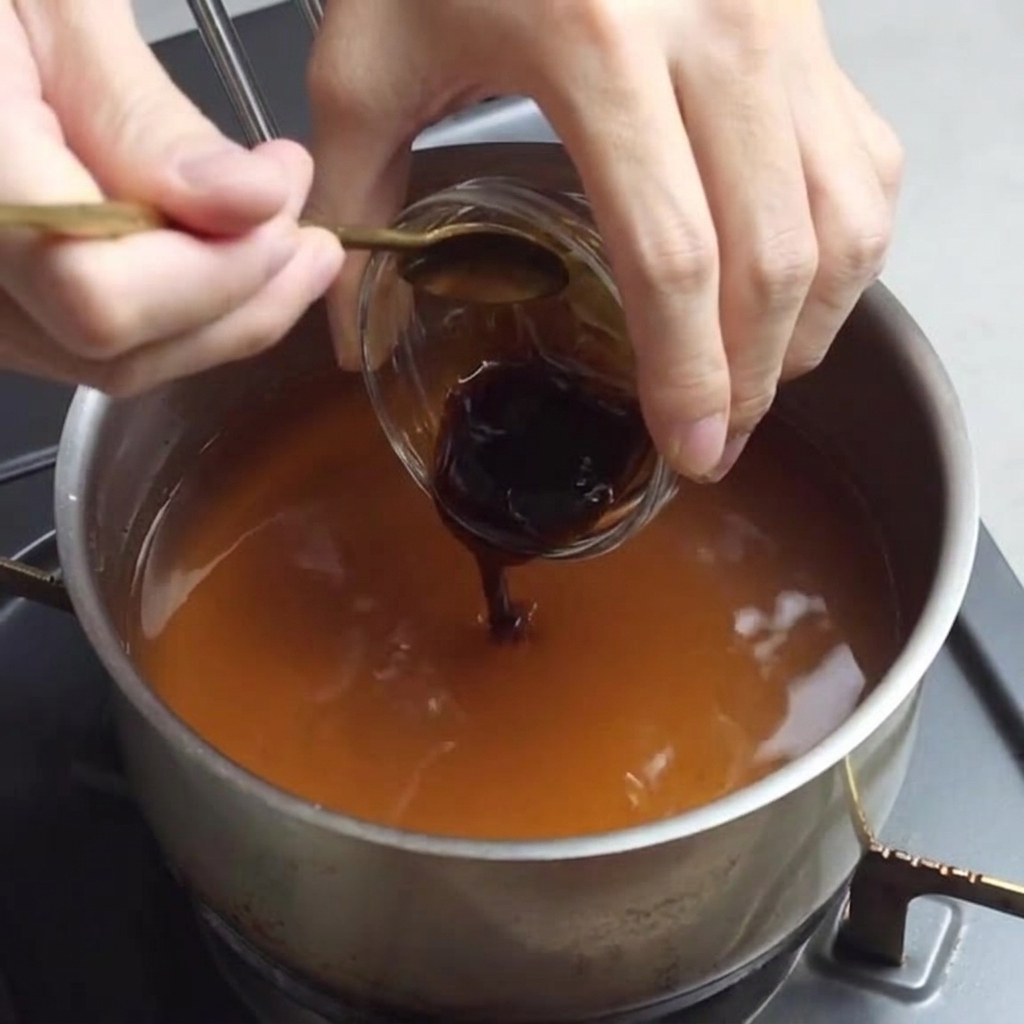Dodawanie sosu ostrygowego do mieszanki bulionu ramen.
