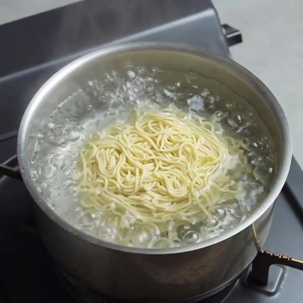 Świeży, żółty makaron ramen gotujący się we wrzącej wodzie.