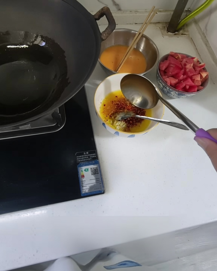 Gorący olej wlewany z chochli do małej miseczki z posiekanym czosnkiem i chili.
