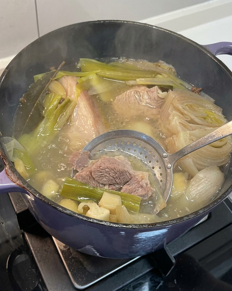 Usuwanie zmiękczonej cebuli, czosnku i imbiru z gotowego wywaru wieprzowego.