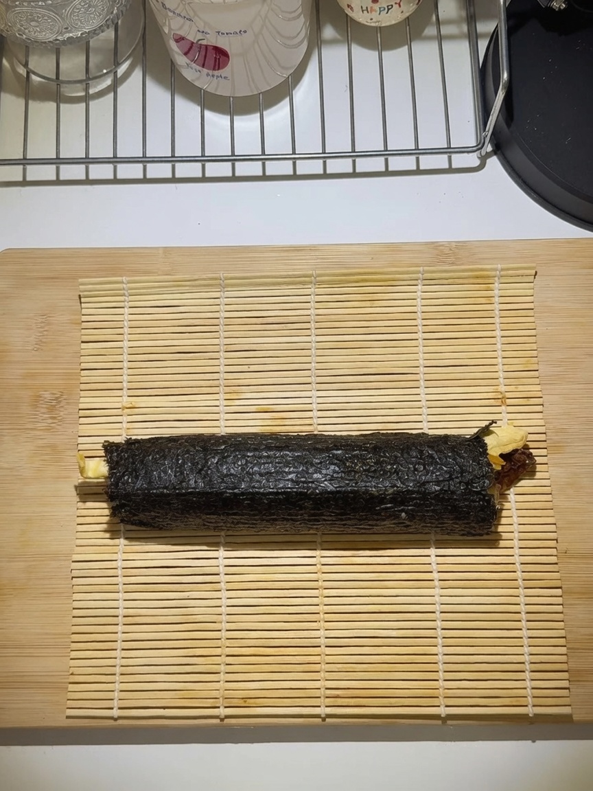 Szczelnie zwinięta rolka gimbap na bambusowej macie.