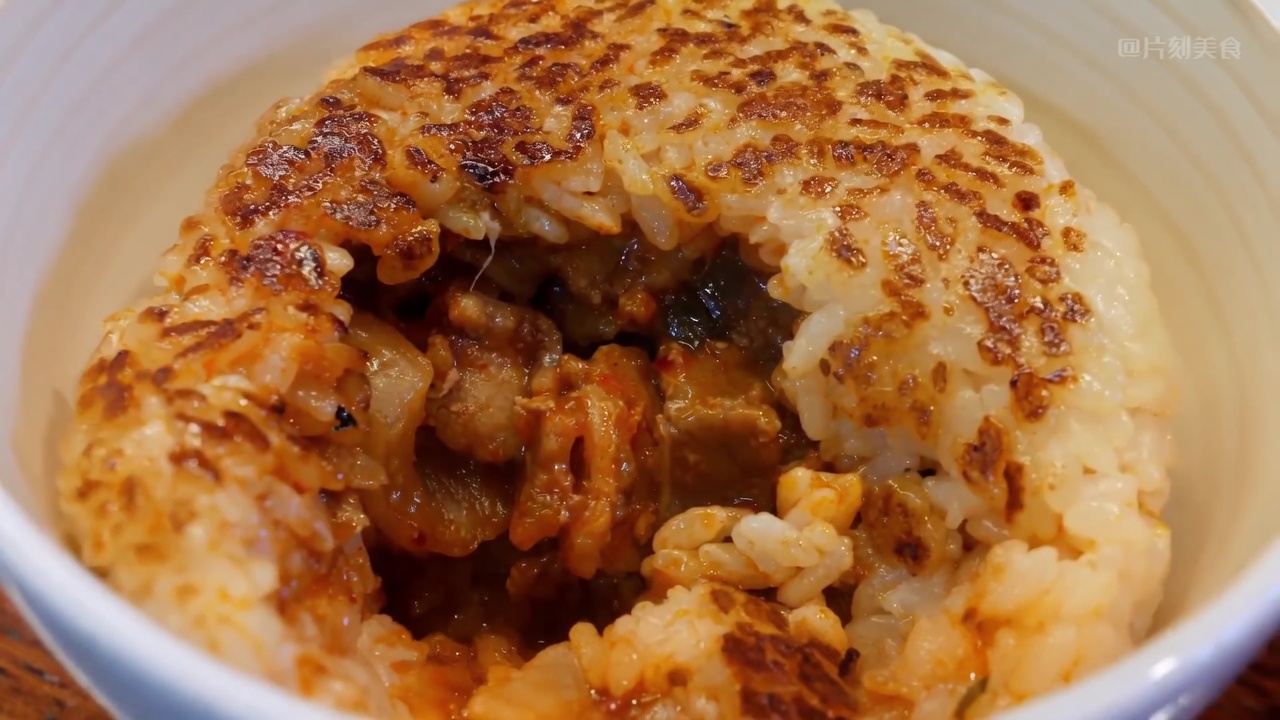 Przekrojona na pół grillowana kulka ryżowa, ukazująca pikantne nadzienie z kimchi i boczku w chrupiącej otoczce.