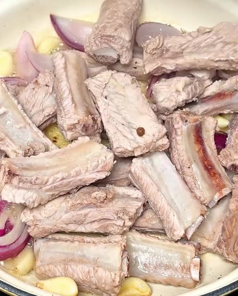 Żeberka wieprzowe smażone w garnku z czosnkiem i cebulą.