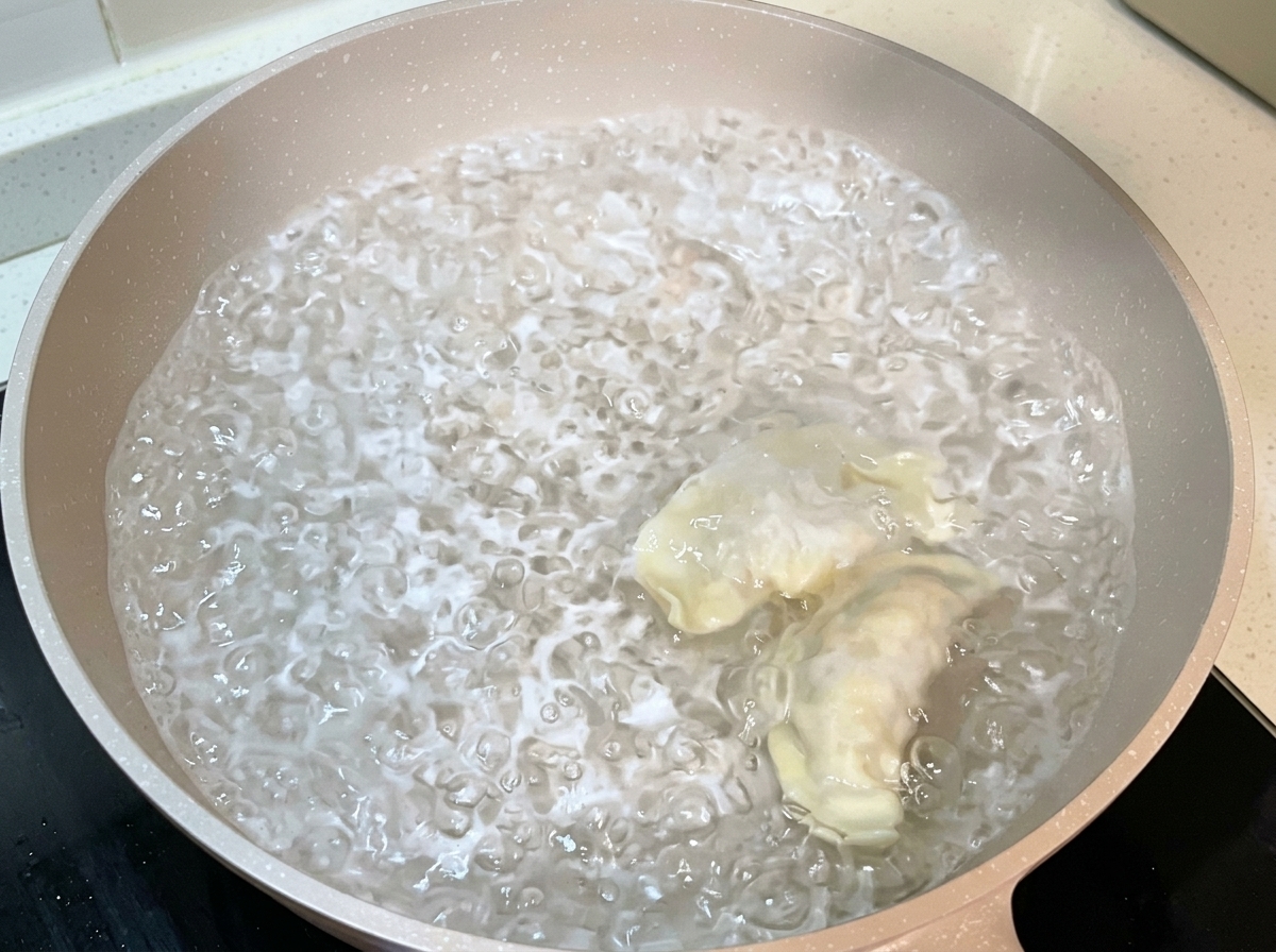 Pierogi wrzucane do garnka z gotującą się wodą.