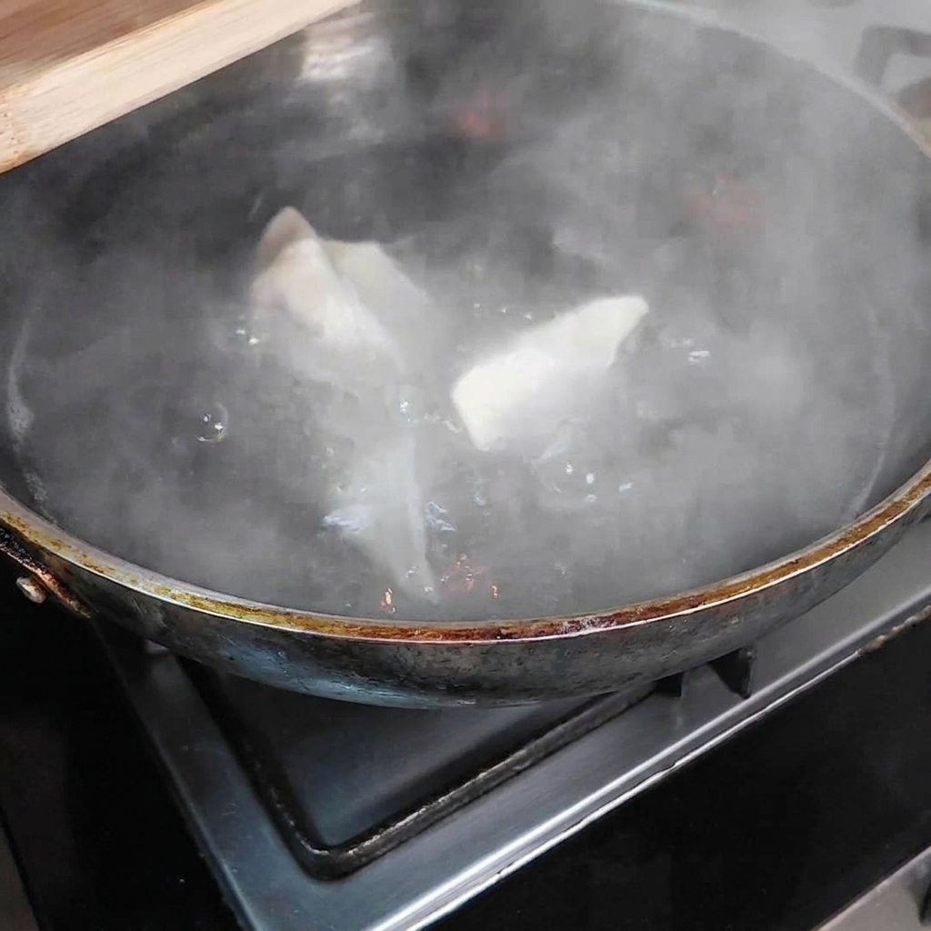 Pierożki gotujące się w garnku z wrzącą wodą.