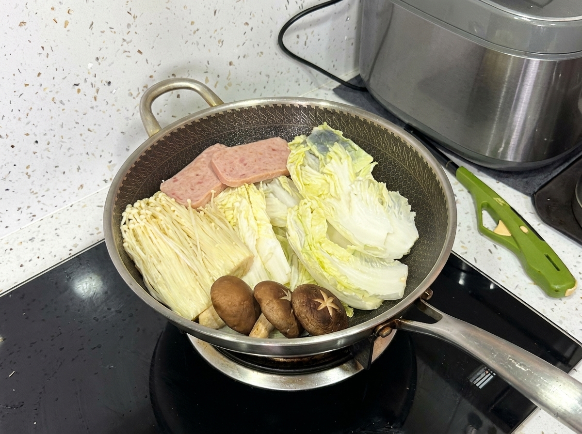 W pełni ułożony wok zawierający kapustę napa, grzyby enoki, grzyby shiitake, mielonkę i plasterki wieprzowiny.