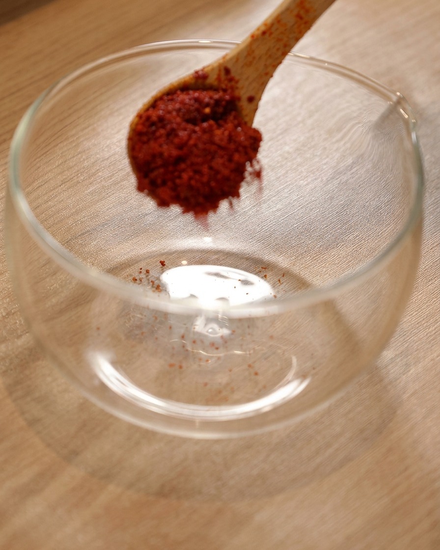 Proszek chili w szklanej misce z dodatkiem koreańskiego ostrego sosu i jasnego sosu sojowego.