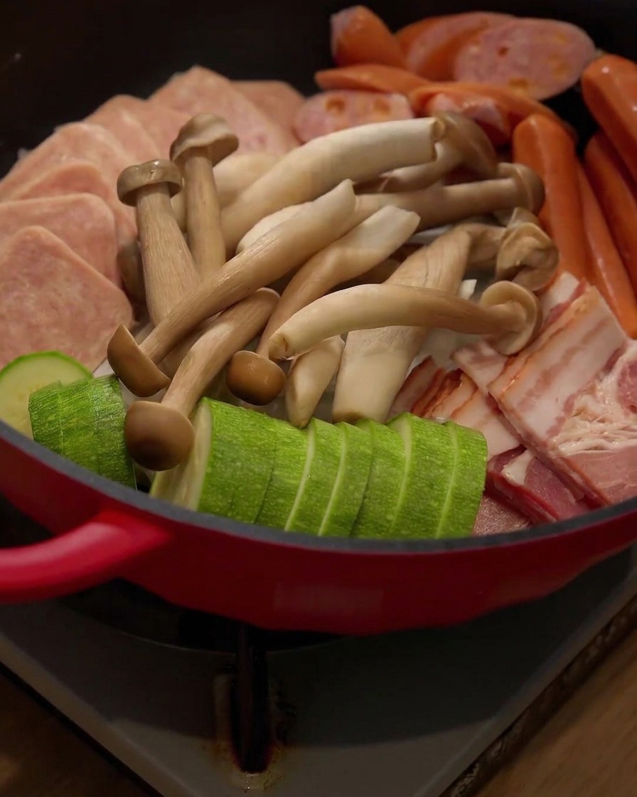 Świeże grzyby enoki dodawane do układu składników w garnku.