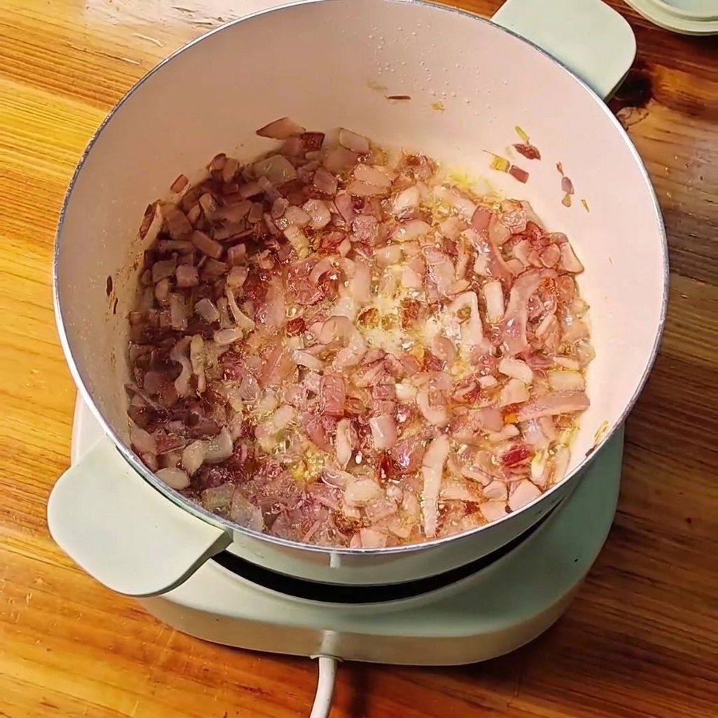 Czosnek i imbir dodawane do podsmażonej czerwonej cebuli w garnku.
