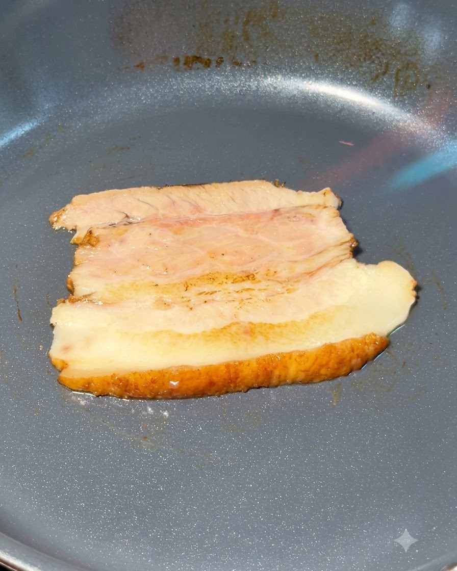 Plasterki boczku chashu opalane palnikiem wewnątrz patelni.