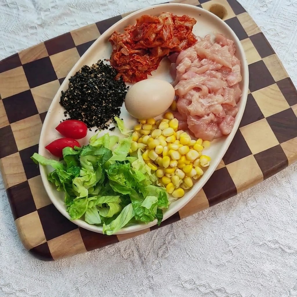 Pokrojona w kostkę pierś z kurczaka w misce wymieszana z przyprawami, imbirem i czosnkiem.