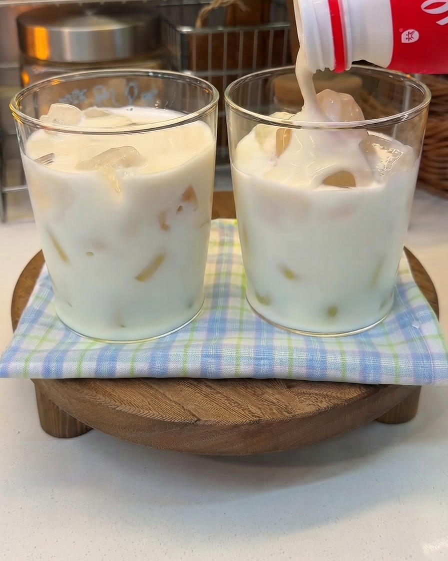 Gęsty jogurt wlewany z butelki do szklanki z zamrożonym mlekiem.