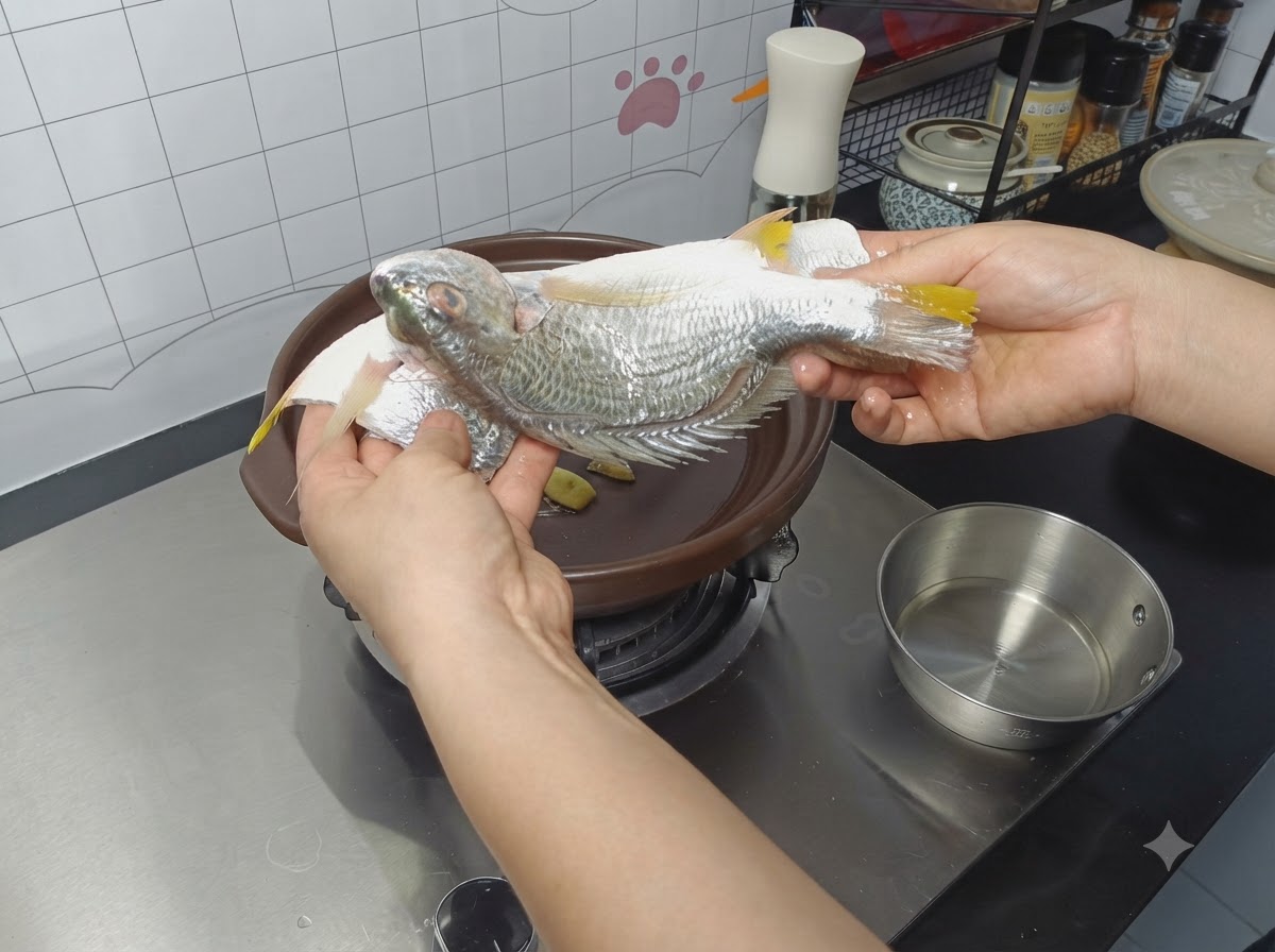 Doprawiona cała ryba umieszczana w glinianym garnku na plasterkach imbiru.
