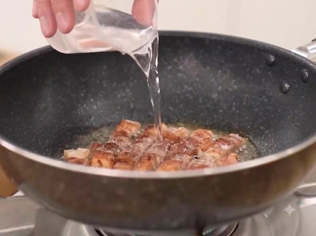 Woda, grubo mielona papryka chili i kimchi dodawane do patelni z usmażonym boczkiem.