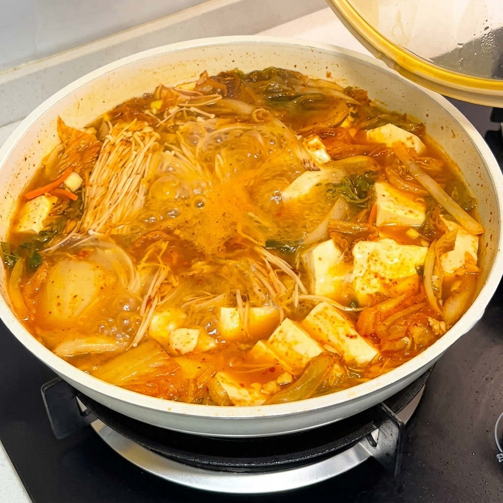 Łyżka sosu z koreańską pastą chilli wlewana do bulgoczącego garnka z zupą.