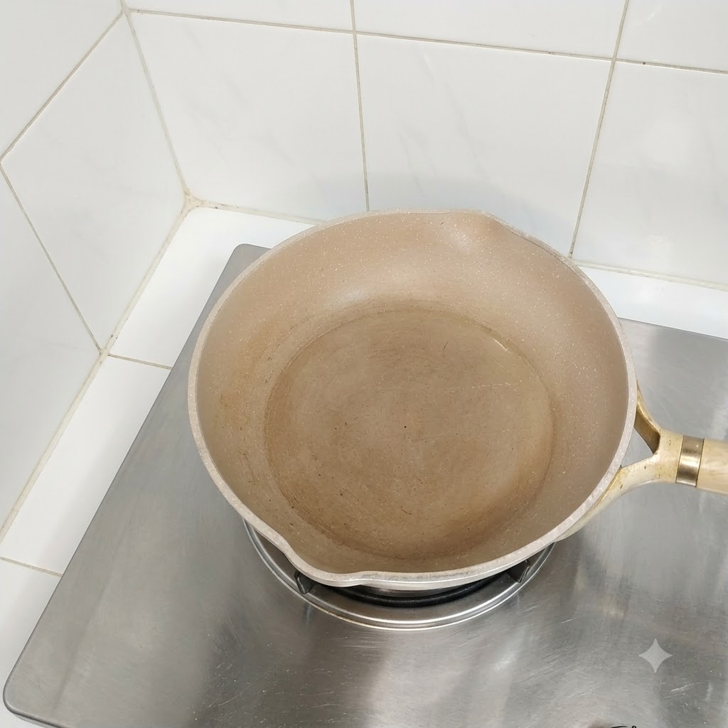 Pusta, naoliwiona patelnia stojąca na palniku kuchenki gotowa do gotowania.