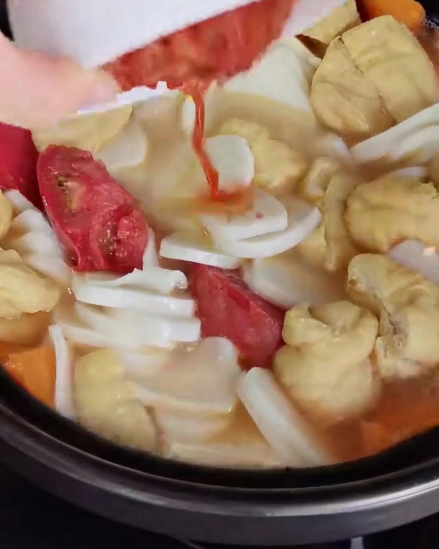 Posiekane kimchi wrzucane i mieszane w bulionie zupy.