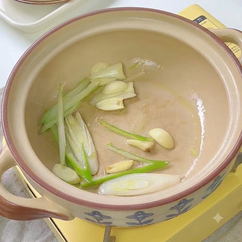 Kimchi podsmażane z zieloną cebulką i czosnkiem w ceramicznym garnku.