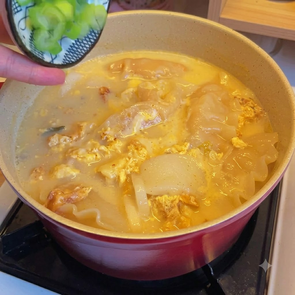 Świeżo posiekana zielona cebulka posypywana na garnek z zupą z pierożkami z kimchi.