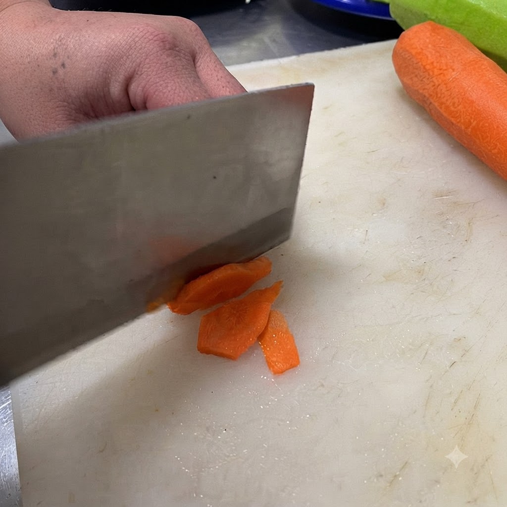 Nóż krający zielone chili na plasterki na białej desce do krojenia.