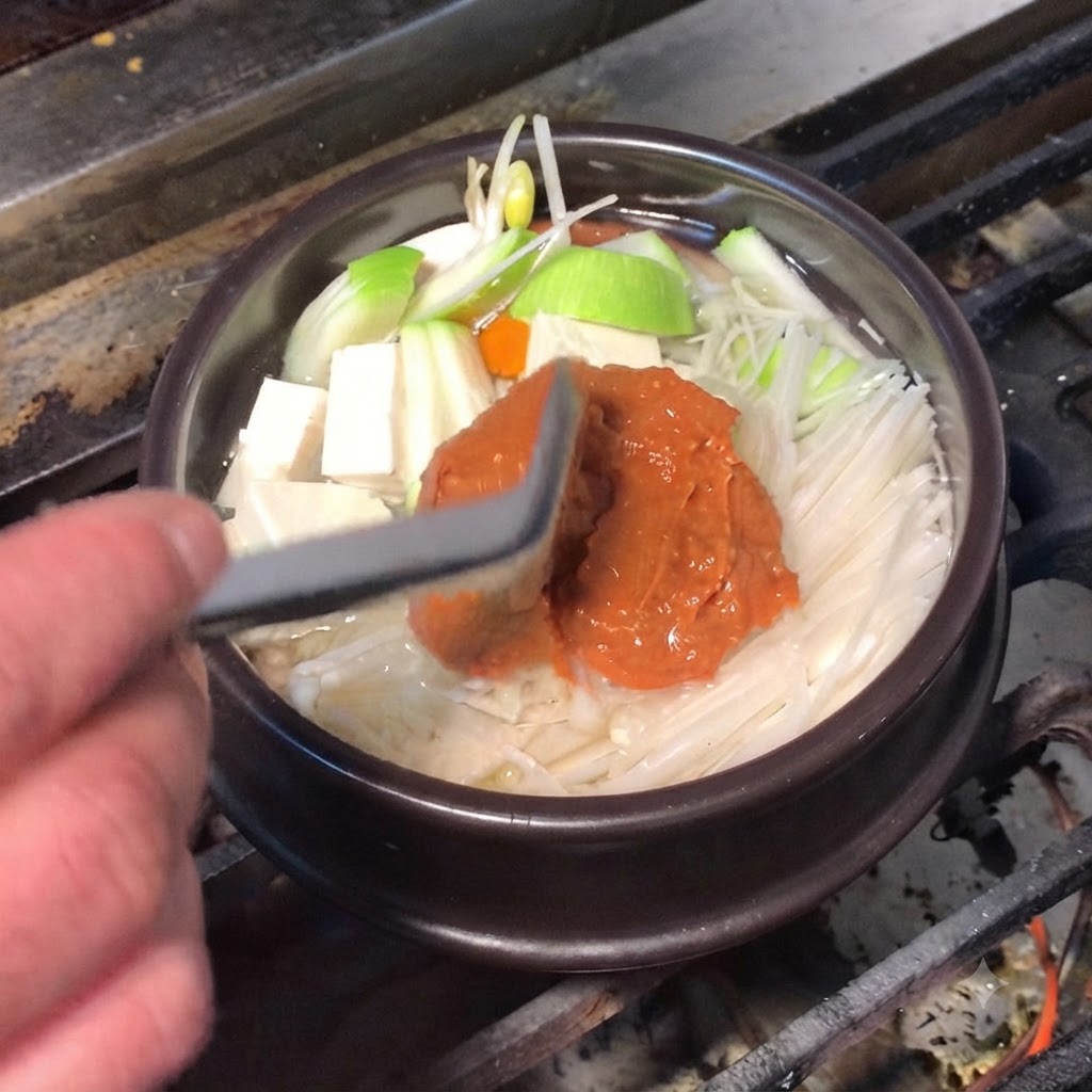 Silikonowa łopatka dodająca bogatą brązową pastę sojową i czerwoną pastę chili do garnka.