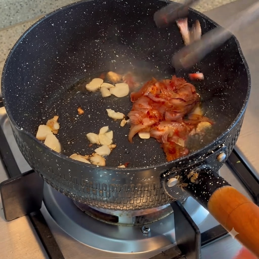 Kimchi wrzucane i podsmażane z podsmażonym czosnkiem w garnku.