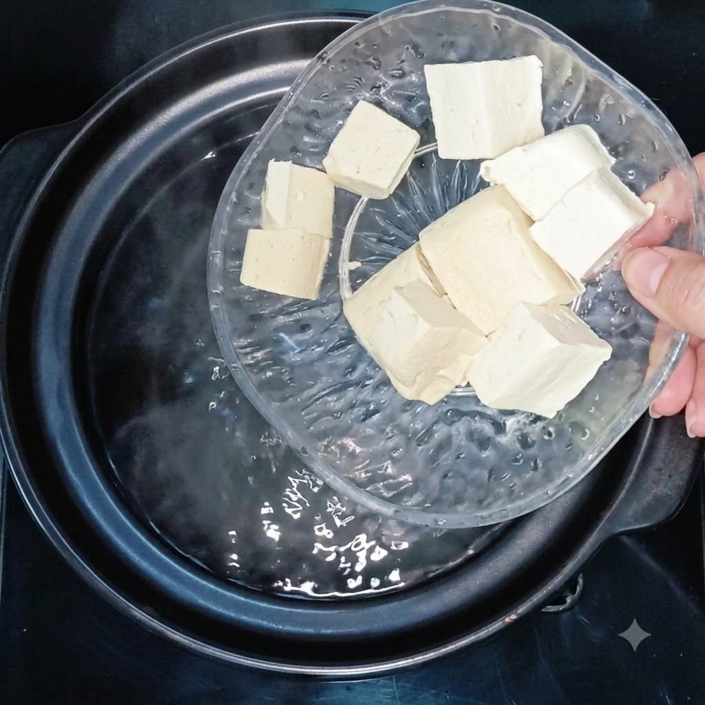 Kostki tofu wrzucane do garnka z gotującą się wodą.