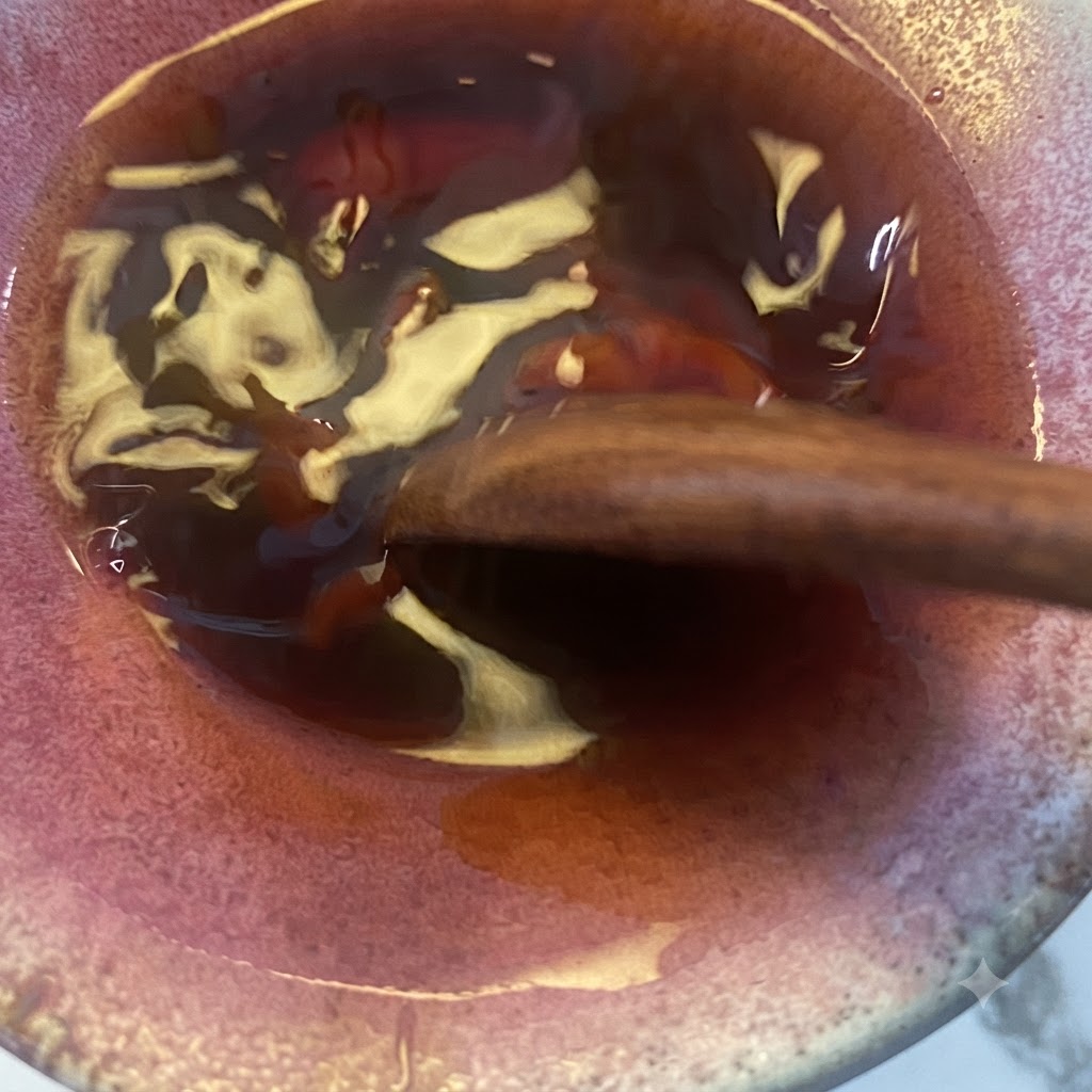 Mieszanka sosu teriyaki mieszana drewnianą łyżką w misce.