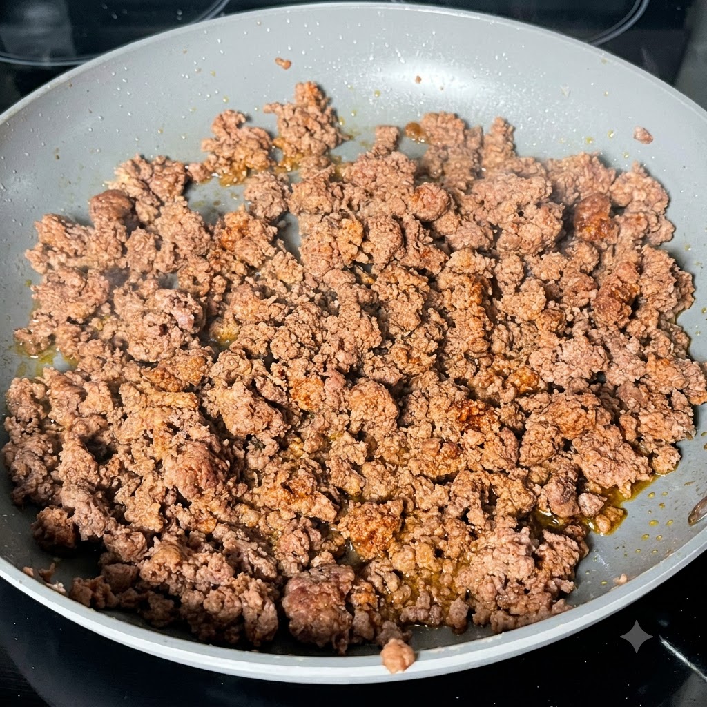 Ciemny sos Worcestershire skraplany na zrumienione mielone mięso na patelni.