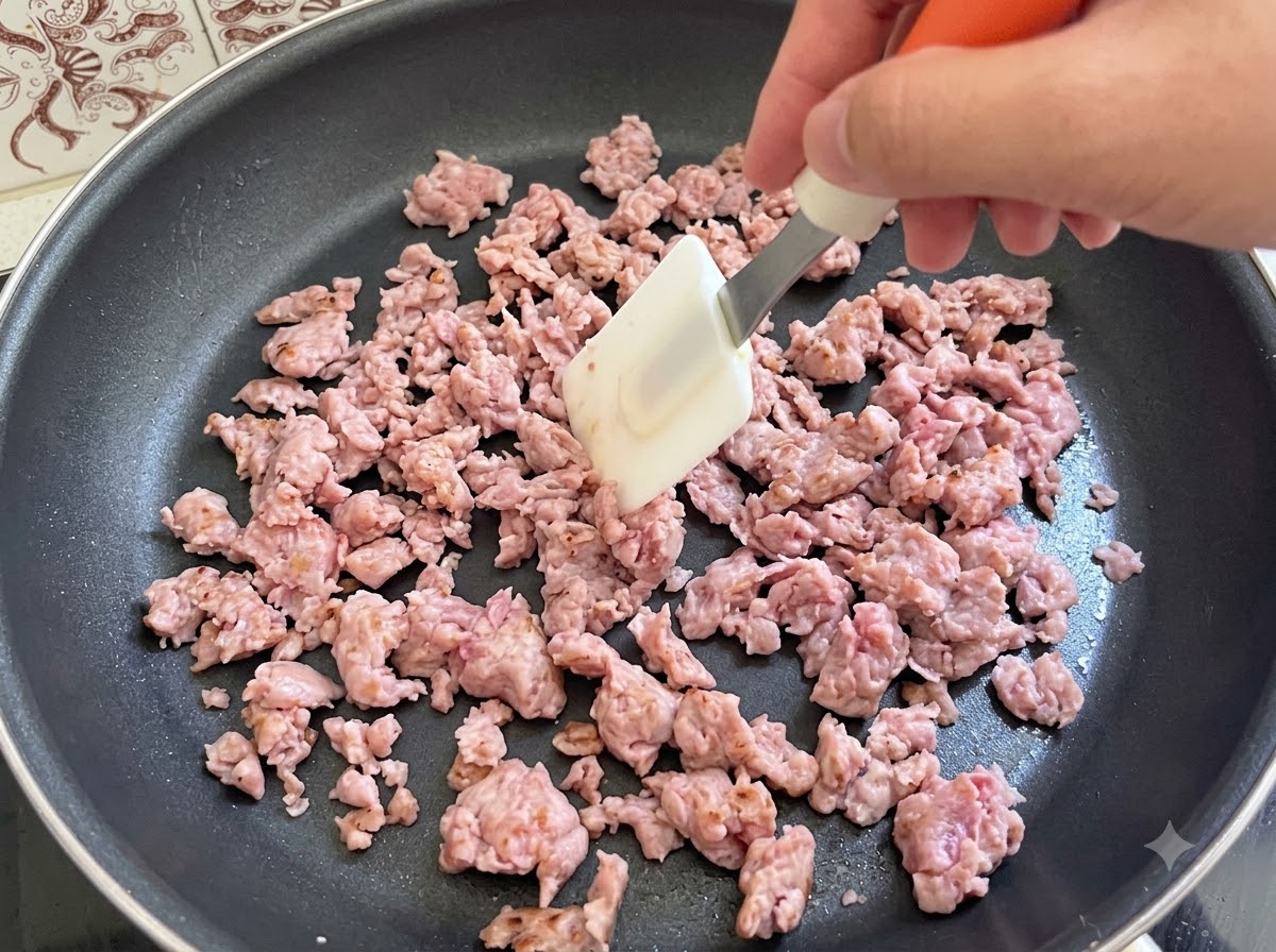 Włoskie mięso kiełbasiane aktywnie mieszane i smażone za pomocą łopatki na patelni.