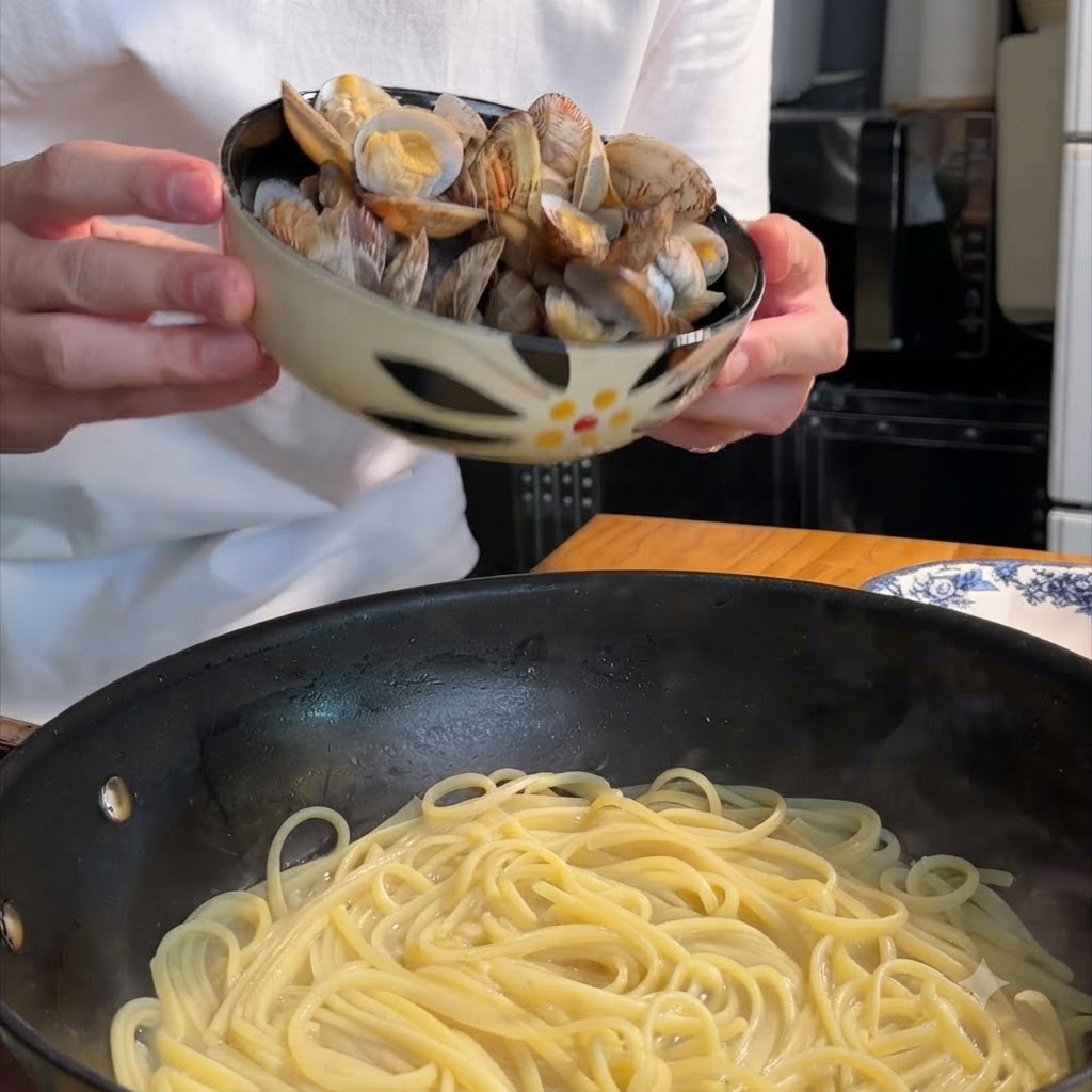 Osoba trzymająca wzorzystą miskę i wrzucająca ugotowane małże na patelnię wypełnioną spaghetti.